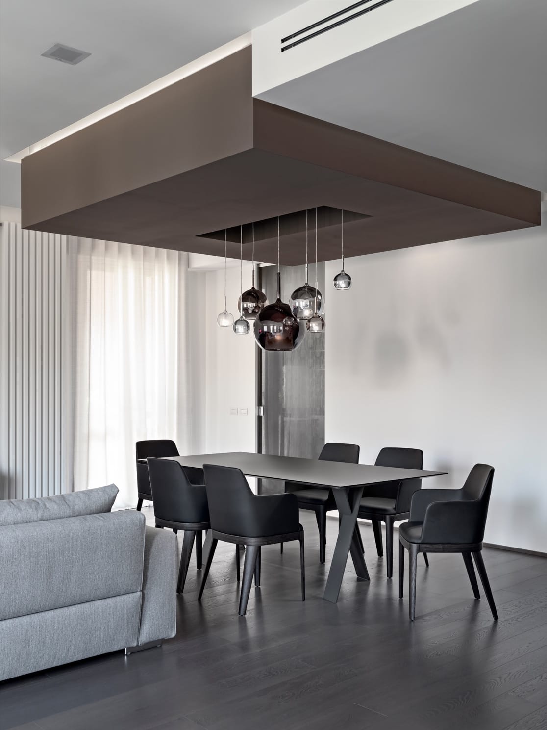 Open-plan dining and living area in a Best World residence with sculptural pendant lighting and a black dining table