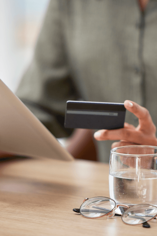 Hands holding eyeglasses and a phone over financial paperwork